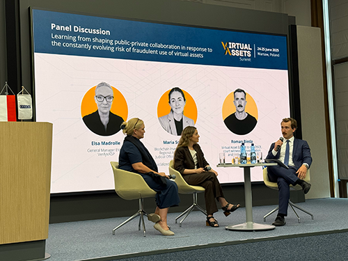 Four panelists sit on stage discussing public-private collaboration on virtual assets. A large screen behind them displays their names, photos, and the panel topic at the Virtual Assets Summit in Warsaw, Poland.