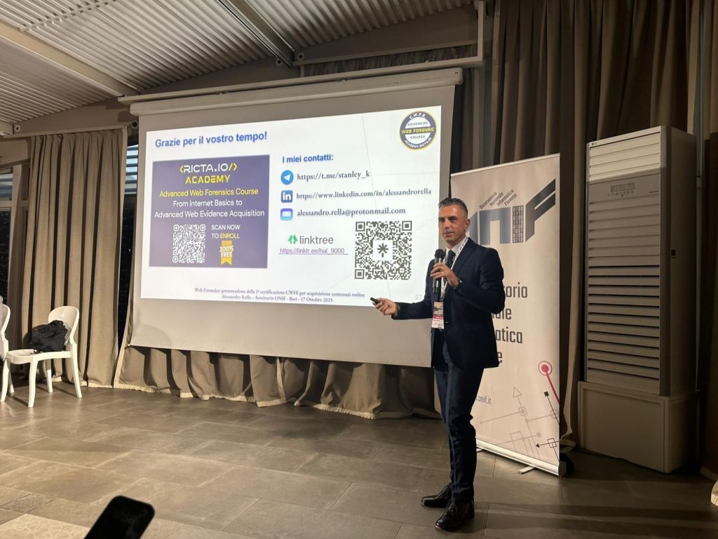 A man in a suit gives a presentation, pointing to a screen displaying contact details, QR codes, and information about the RICFATA-IO Academy. Chairs and a podium are visible in the room.